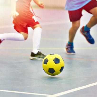 Zaalvoetbal: gele bal en de benen van drie spelers